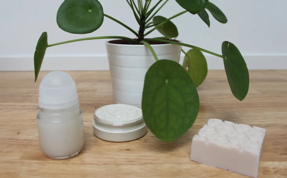 Un déodorant, une crème et un savon faits maison posés sur une table en bois