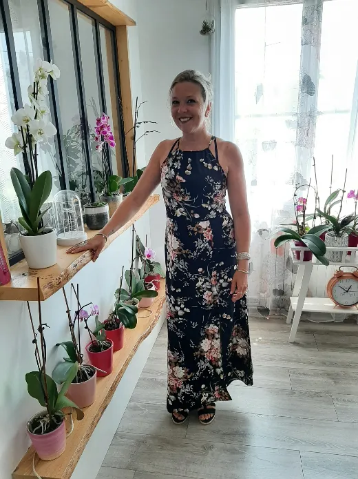 Edwige, souriante, devant des étagères d'orchidées